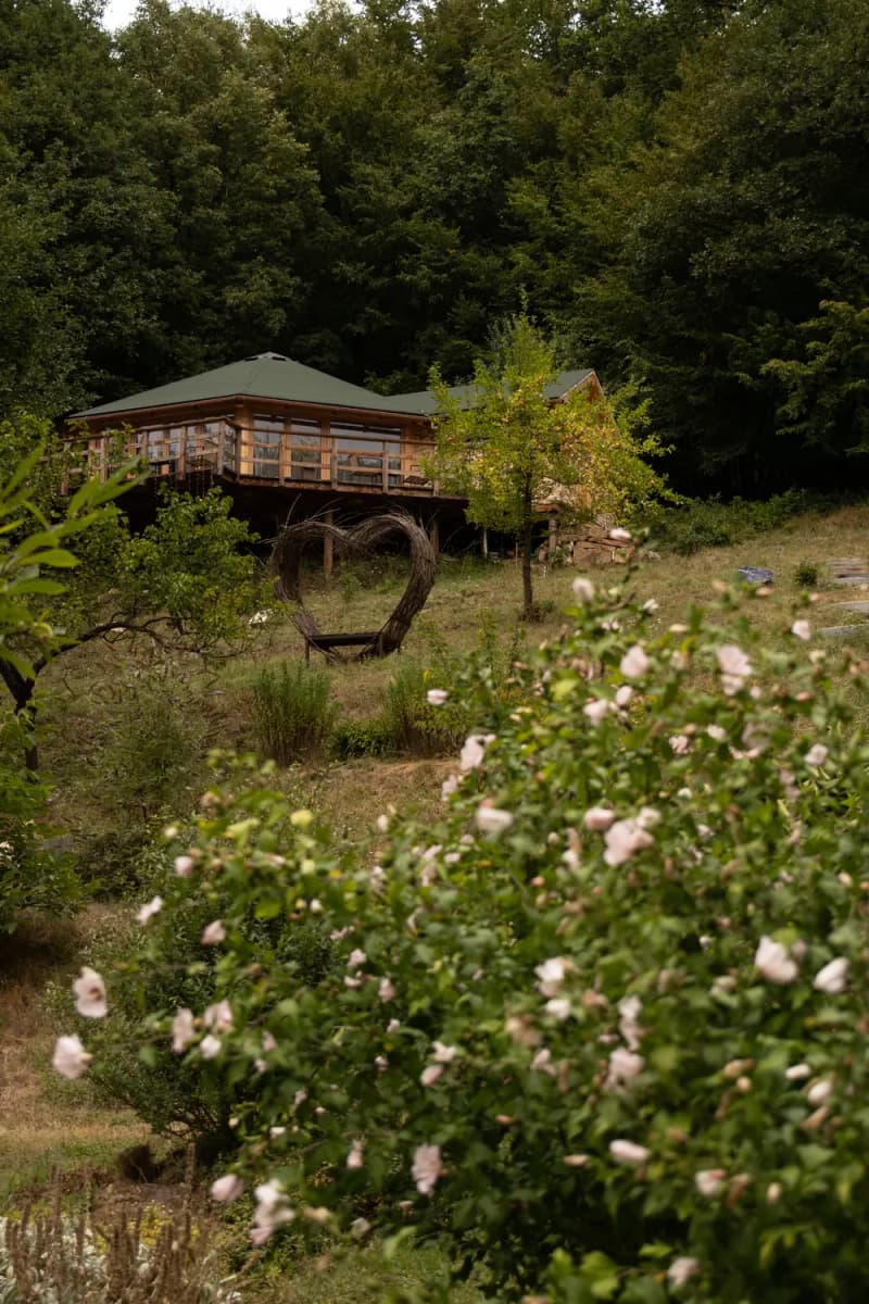Shalla — dřevěná stavba nad zahradou s proutěným srdcem